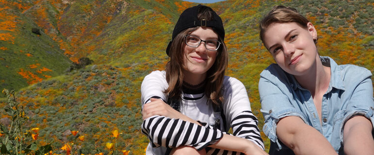 Teens sitting a field of grass and flowers